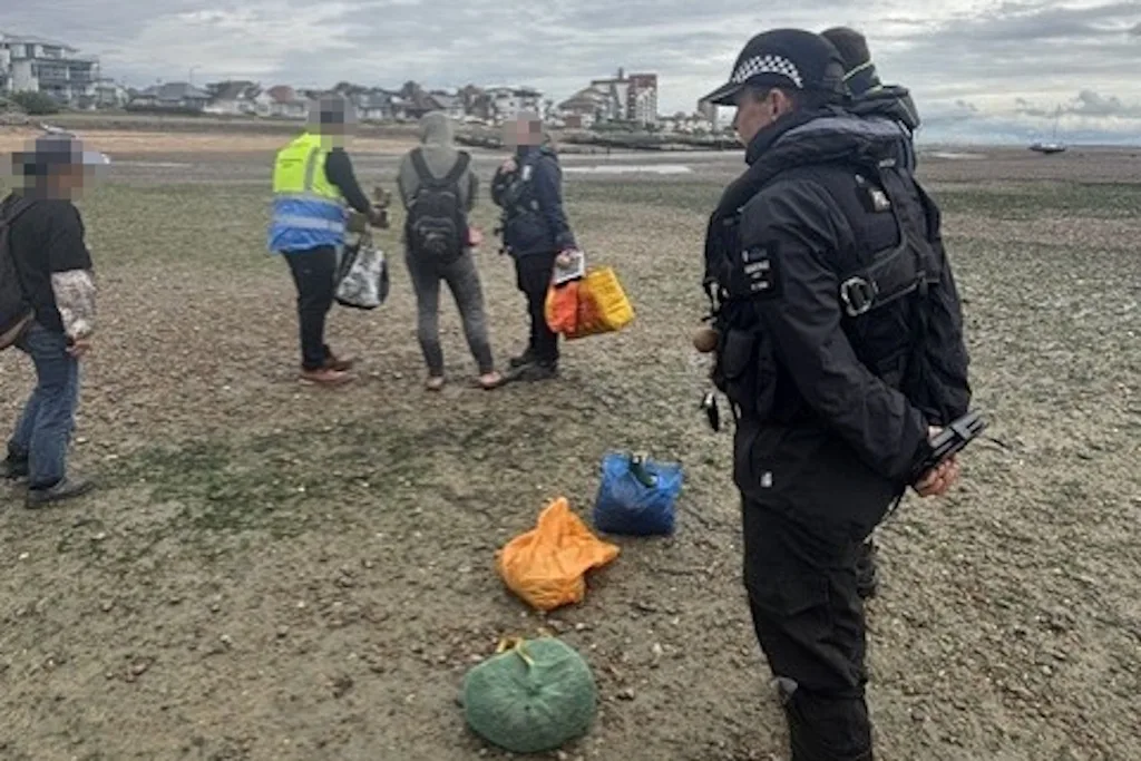 Officers speak to shellfish gatherers on Chalkwell beach at low tide, with bags of shellfish on the foreshore. Essex Police blurred the faces before publishing the photo