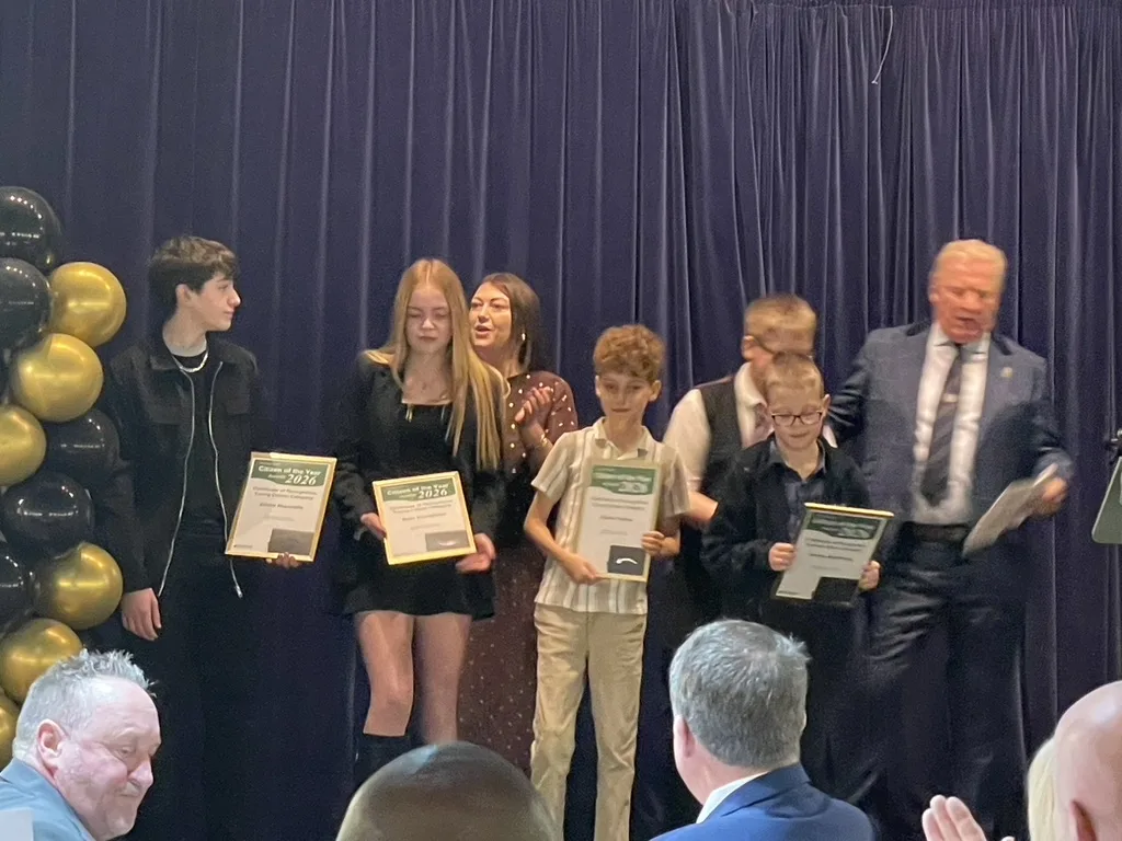 Young people holding certificates on a stage with gold and black balloons at the Rayleigh Citizen of the Year awards